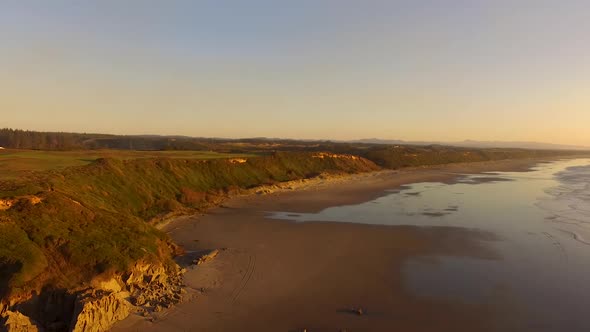 Drone descending over Whiskey Run, a beach near Bandon at the Southern Oregon coast during sunset