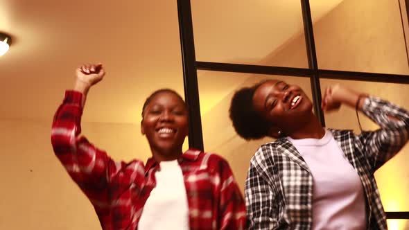 Two Happy Sisters Dancing in Living Room at Evening