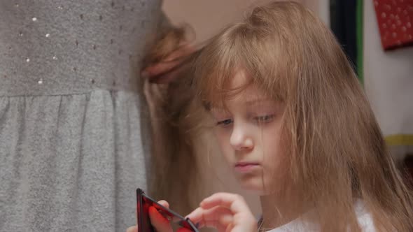 Young Woman Combing Girl