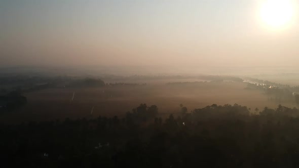 Aerial shot of Beautiful sunrise over paddy field,Golden lights, Morning shot with mist,