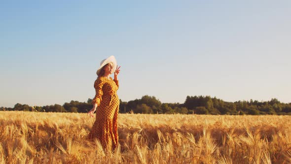 Pregnant woman in the rays of the sunset in the field