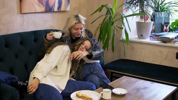 Happy Lesbian Lgbtq Couple in Love Cuddling Laughing Drinking Coffee Having Fun Relaxing on Couch at
