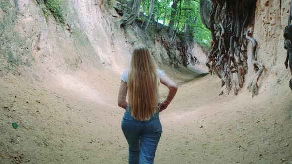 Back View of Pretty Blonde Woman Walking in Natural Loess Ravine