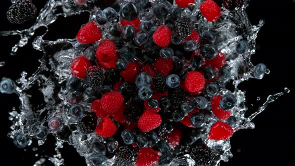 Super Slow Motion Shot of Rotating Exploded Berries Fruit with Splashing Water on Black at 1000Fps