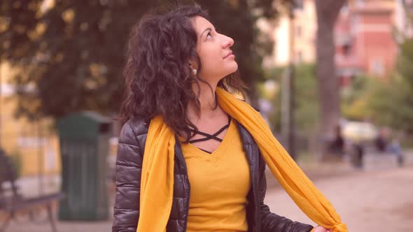 beauty, youth - young woman at the park knots her scarf and looks at the sky