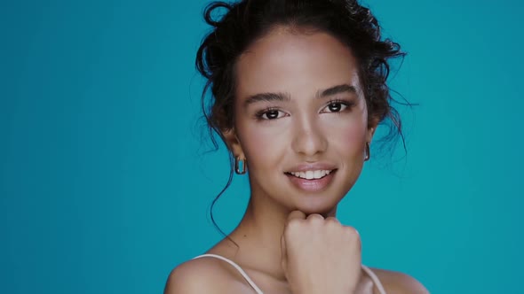 Glamourous Girl with Light Make-up Smiling To Camera and Runs Fingers on Her Face