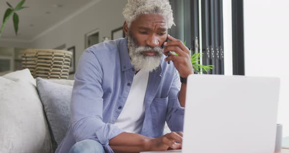 Video of african american senior man using smartphone and laptop