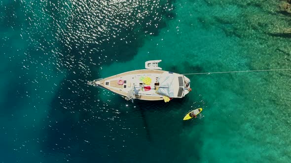 Aerial view of paddle board next to boat anchored on the coast of Varko, Greece.