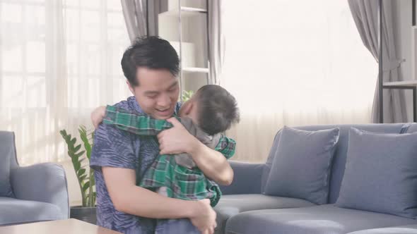 Young Asian Father Hug And Kiss His Son At Home