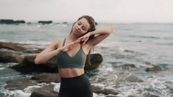 Lady Poses for Camera Touching Long Hair Against Ocean Waves