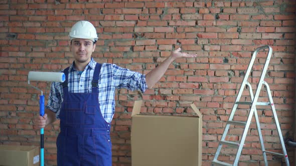 Male Builder in a White Helmet and Uniform Shows His Hand To Copyice