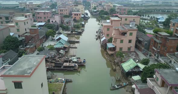 Aerial shot of  an asian village located along polluted river with moored boats