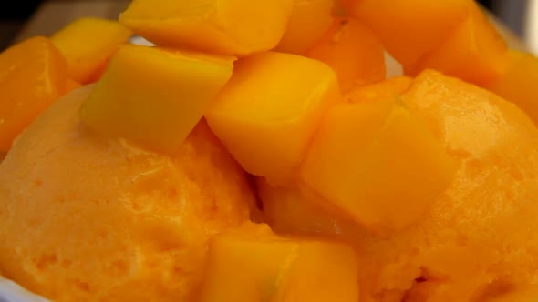 Cubes of Fresh Mango are Falling in a White Bowl Full of Frozen Mango Icecream