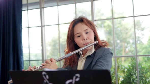 Asian woman teacher in business suit she teaches classical music Playing the flute