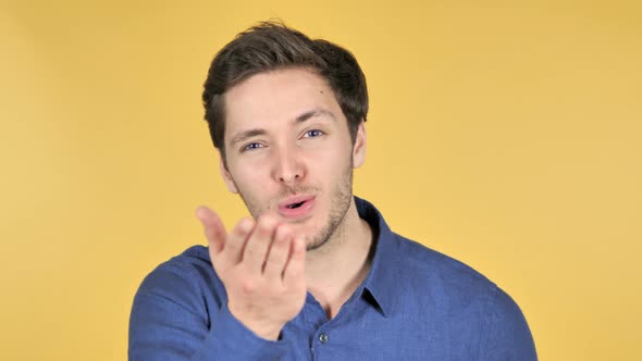 Flying Kiss by Young Man Isolated on Yellow Background