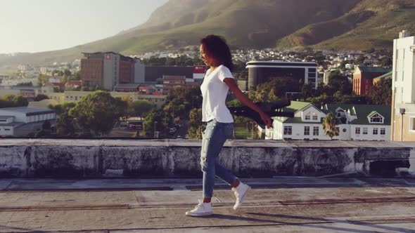 Fashionable young woman on urban rooftop turning round and swingin her jacket