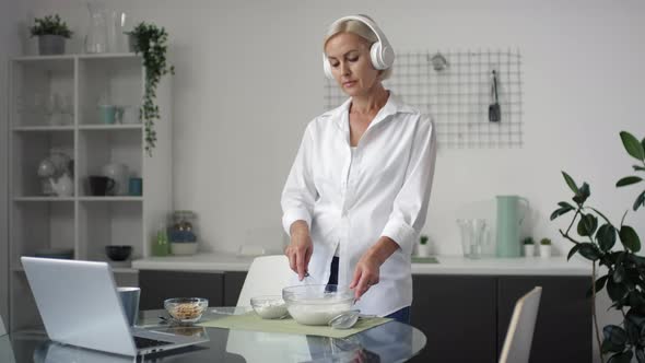 Mid-Aged Woman Enjoying Music while Cooking in Kitchen