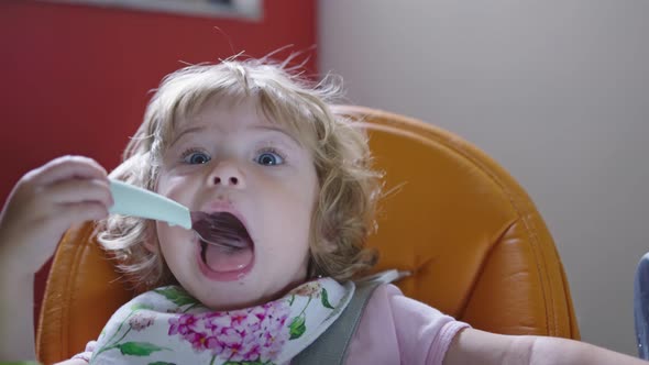 Girl Making Funny Face, Playing with Fork During Feeding Time