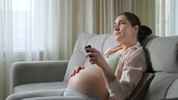 Bored Pregnant Woman Switches TV Channels Stroking Belly