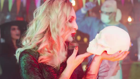 Beautiful Woman in a Vampire Halloween Costume with a Skull in Her Hands