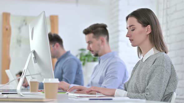 Focused Creative Team Working on Desktop in Modern Office