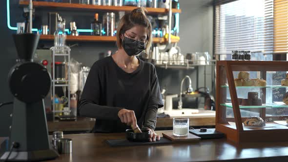 4K Asian woman barista making iced matcha green tea latte serving to customer at cafe