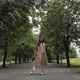 A Girl in a Brown Cloak Stands in a Park and Poses for the Camera - VideoHive Item for Sale