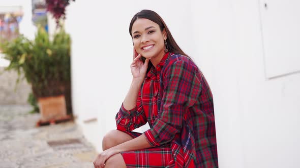 Smiling Ethnic Woman Sitting on Street