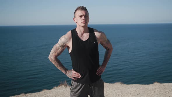 Tattooed Sportsman Does Workout Outdoors, Beautiful Sea View on Background