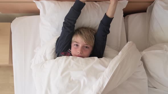 Funny kid under blanket at the morning.