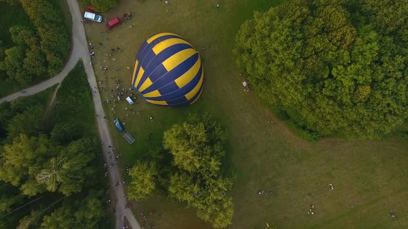Several Air Balloons Lying on Ground and Getting Inflated Surrounded by Crowd