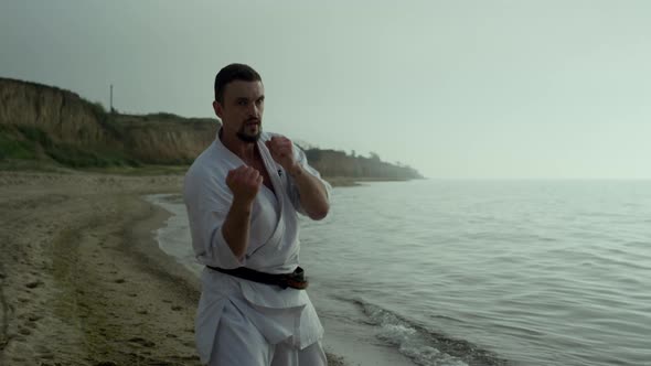 Strong Fighter Exercising Punches on Beach Close Up