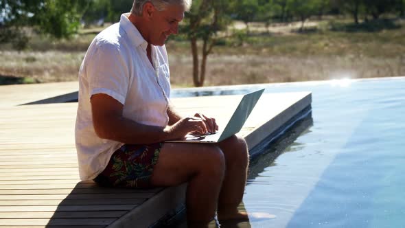 Man using laptop near poolside 4k