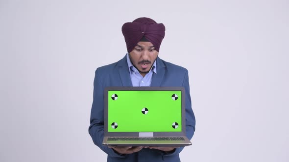 Happy Indian Sikh Businessman Showing Laptop and Looking Surprised
