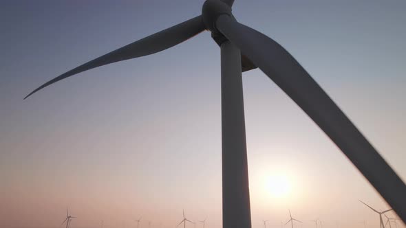 Close-up of wind turbine blades at sunset or sunrise.