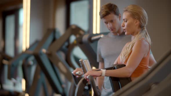 Sporty Fit Girl Making Bicep Curls in Sport Club. Trainer Giving Advice at Gym alt