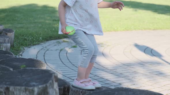 Cute Pretty Child Jumping on Wood Stumps