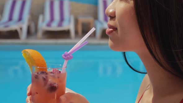 Portrait of Young Asian Woman Sitting on Poolside, Enjoying Drinking Cool Fruit Cocktail, Close Eyes