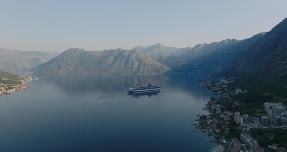 cruise liner in kotor bay during sunrise with mountains on background aerial drone view