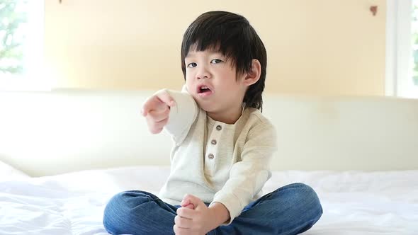 Unhappy Child Sitting On Bed