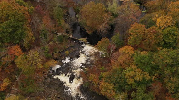 An aerial drone shot of the colorful fall foliage in upstate NY. The camera boom up & pan right over