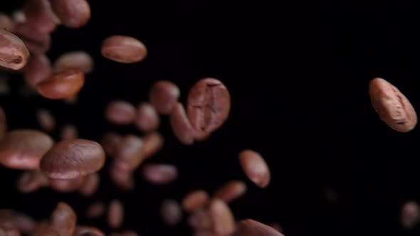 Close-up of Roasted Coffee Beans Flying Diagonally on the Black Background