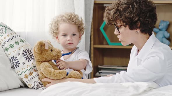 Toddler Playing Doctor with Plush Bear alt