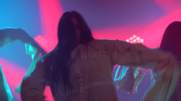 Silhouettes of a Three Charming Girls in White Shirt Are Dancing on the Stage. Shot in a Dark Studio