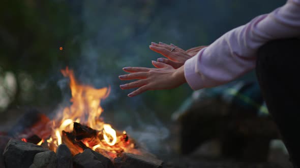 Hands warming at a campfire