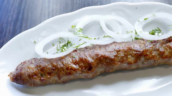 Beef Kebab with Onion Rings on a White Plate