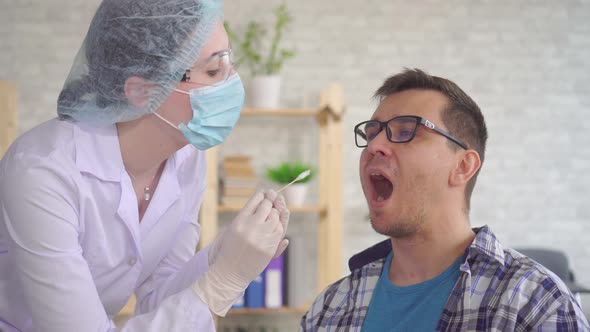 Woman Lab Technician Taking a Saliva Test From a Man's Mouth with a Cotton Swab