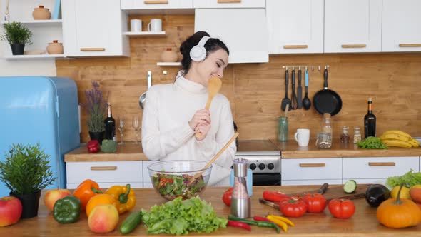 Young Woman Singing In The Kitchen Wearing Headphones