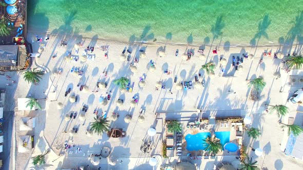 Flying above straw umbrellas on white beach of Pag island in the morning