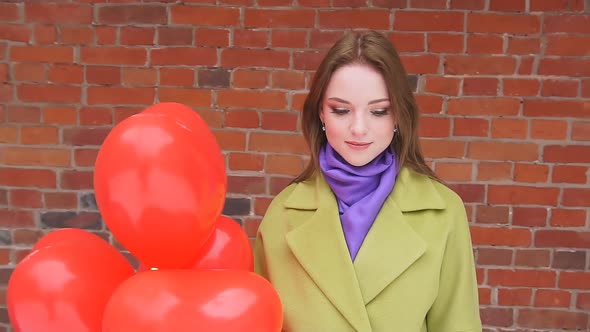 Portrait of a Young Woman with Balloons Against a Red Brick Wall.